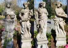 Four stone statues are seen representing ancient Greek goddesses.