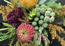 A flower arrangement with various types of flowers and greenery is displayed.