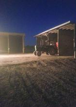 A tractor parked outside of a shed at night.