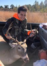 A boy holds the antlers of a large deer.