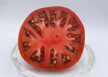 A sliced tomato sits in a glass dish.