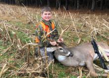 A boy displays a harvested buck.