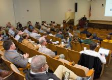 People in an auditorium watching a person give a presentation.