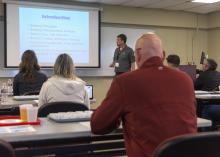 A man lectures from the front of a classroom.