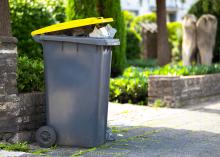 Full trash can sitting at the curb awaiting collection