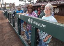 A group of people stand in a baseball dugout.