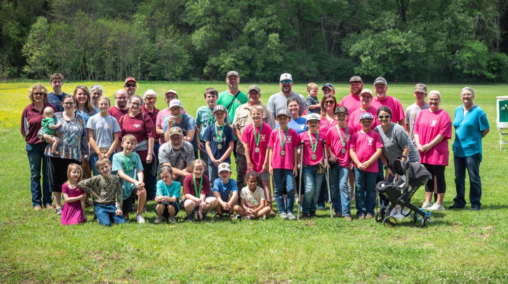 A large group of adults and children gathered on a grassy plain.