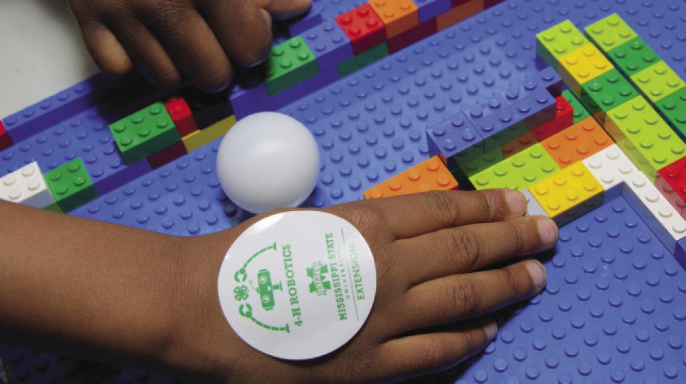 A child uses colorful LEGO bricks at a 4-H Robotics competition.