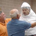 Kipp Brown, left, Extension area livestock agent based in Carroll County, assists Al Fulton, safety officer with the Mississippi Board of Animal Health, as they adjust the security hood on Charlie Stokes, area agronomics crops agent based in Monroe County. (Photo by Linda Breazeale)