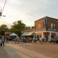 Sunset over a brick downtown filled with people milling about.