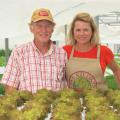 A man and woman behind plants in a greenhouse.