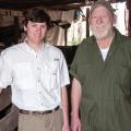 An older man and a young man stand next to each other smiling.