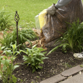 A person spreading mulch in a flower bed.