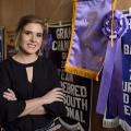 A woman stands in front of several award ribbons.