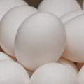 A close up of white eggs stacked in a bowl with other white eggs.