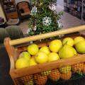 A wooden and wire basket full of yellow and orange fruit sits indoors with a Christmas tree in the background.