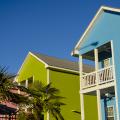 Palm trees adorn the landscape in front of blue, green and pink cottages.