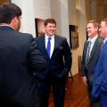 Four men in business suits talking to each other and laughing.