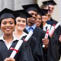 A group of smiling graduates pose in caps and gowns.