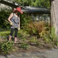 A woman uses a hoe to tend a flower bed.