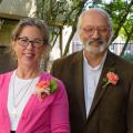 A man and a woman pose in a garden.