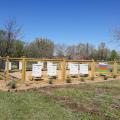 A fenced area encloses several beehives. 