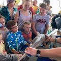 Children feel the skin of a shark held by a marine fisheries biologist.