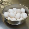 White eggs fill a metal bowl on a countertop.