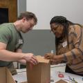 A man and a woman work together with a box.