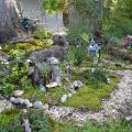 A pea gravel trail surrounds a miniature fairy village under a tree.