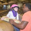 Emma Welch, 5, cannot take her eyes off her side walker, Rufus Warren, a senior in the Mississippi State University School of Human Sciences. The two were demonstrating hippotherapy activities during the Therapeutic Riding Expo at the Mississippi Horse Park near Starkville April 19, 2016. (Photo by MSU Extension Service/Linda Breazeale)