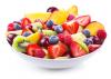 A white bowl of mixed chopped fresh fruits and berries on white background.