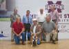 Seven men stand or kneel indoors in two rows, holding a bulldog in the center of the group.