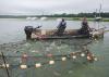 Large nets converge on a boat with two men aboard.