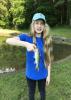 Girl in a blue T-shirt and baseball cap holding a small fish.