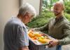 A man delivers a food box to a senior citizen.