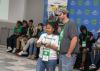 A man looks on as a child controls a remote for a drone.