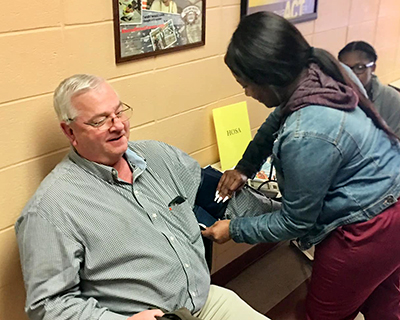 A JMWV checks blood pressure at a local health fair.