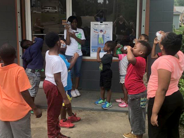 A girl is explaining to community youth about the benefits of water to bodily organs.